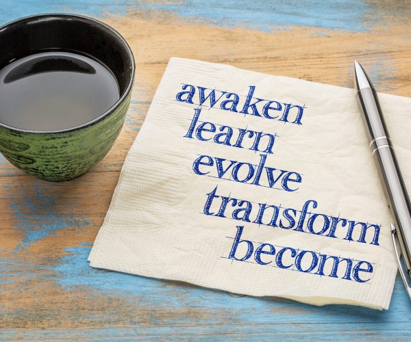 awaken, learn, evolve, transform and become - inspirational words - handwriting on a napkin with a cup of tea